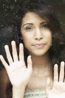 Hispanic woman looking out rainy window