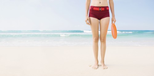 Caucasian woman holding plastic disc on beach