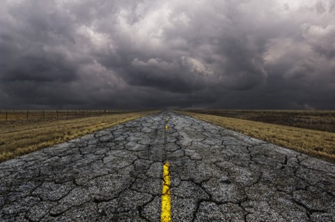 Cracked road under cloudy sky in remote landscape
