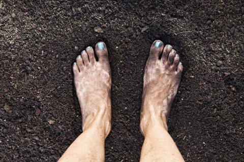 Mixed race woman barefoot in dirt