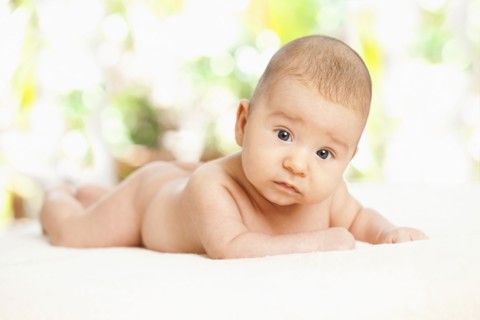 Nude mixed race baby laying on blanket