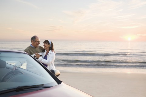 Older couple standing at car on beach
