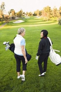 Women carrying golf clubs on golf course