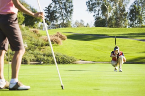 Women planning putt on green at golf course