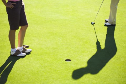 Women putting on green at golf course