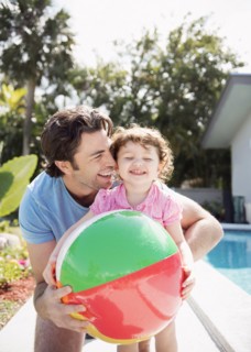 Caucasian father and baby daughter playing with beach ball
