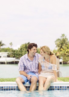Caucasian couple sitting at the edge of swimming pool