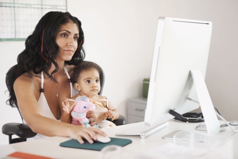 Mixed Race mother using computer and holding baby daughter