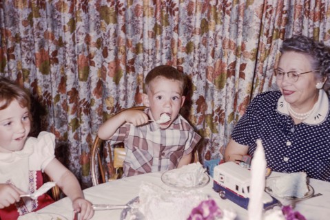 Caucasian woman watching grandson and granddaughter eating cake