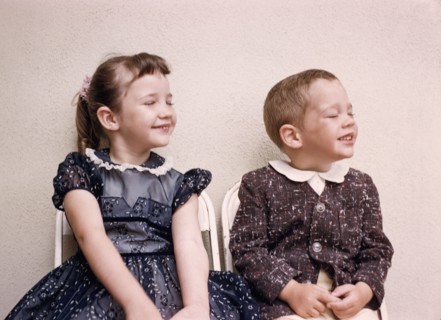 Caucasian brother and sister smiling with eyes closed