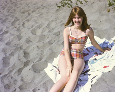 Portrait of smiling Caucasian teenage girl sitting on blanket at beach