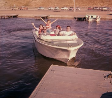 Portrait of smiling Caucasian family waving on boat near dock