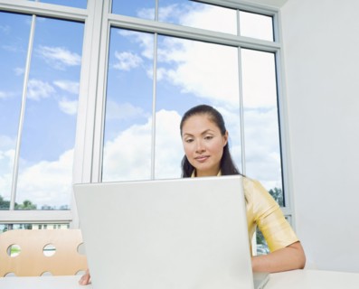 Mixed Race businesswoman using laptop near window