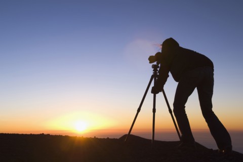 Silhouette of Mixed Race photographer with camera at sunset