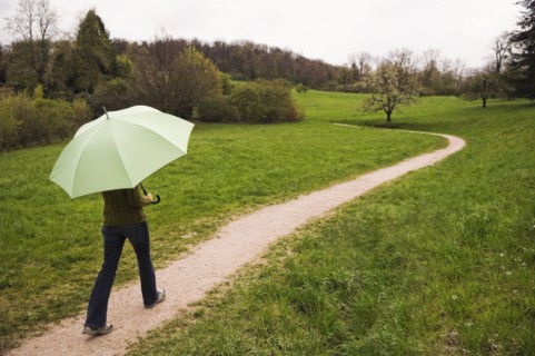 Mixed Race woman carrying umbrella on path