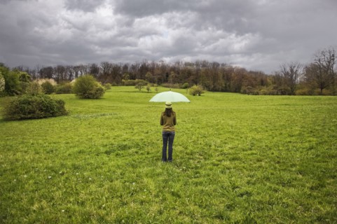 Mixed Race holding umbrella in field