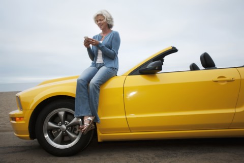 Caucasian woman sitting on convertible at beach