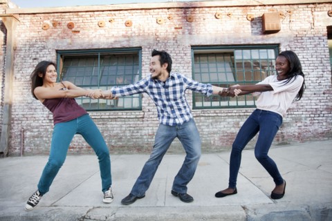 Women pulling on male friend's arms