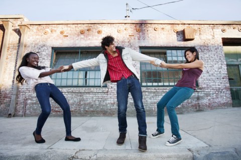Women pulling on male friend's arms