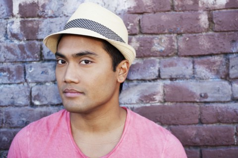 Serious Asian man near brick wall
