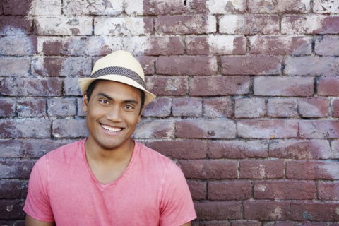 Smiling Asian man near brick wall