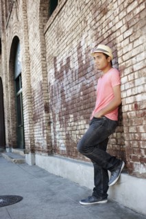Asian man leaning against brick wall