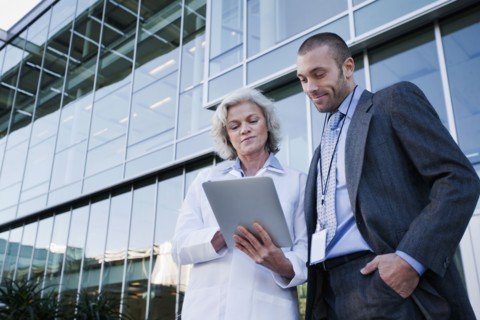 Doctor and businessman using digital tablet outdoors