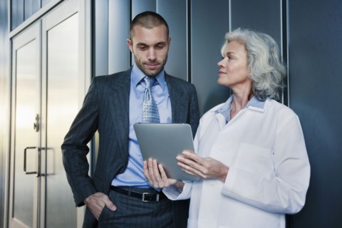 Doctor and businessman using digital tablet outdoors