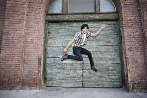 Mixed race man jumping on urban sidewalk