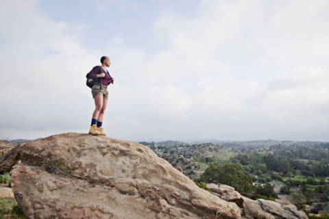 Black hiker standing on rock in remote area