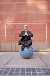 Caucasian businessman practicing yoga on ball inside of box