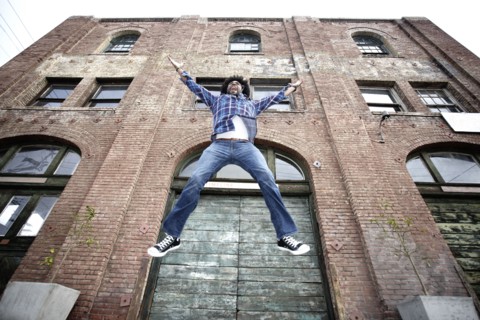 Black man jumping next to urban building