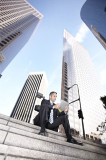 Hispanic businessman sitting on steps with digital tablet