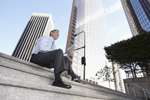 Hispanic businessman sitting on steps with digital tablet
