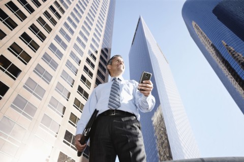Hispanic businessman holding notebook and cell phone outdoors