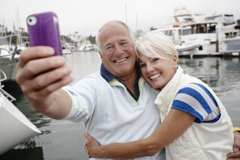 Smiling couple taking self-portrait at marina