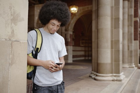 Student with afro text messaging on cell phone