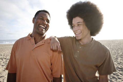 Father and son standing together on beach