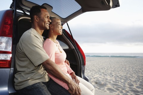 Black couple sitting on hatchback enjoying the beach