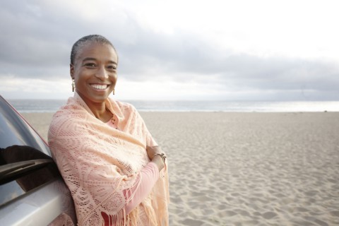 Black woman in shawl standing on beach