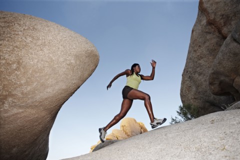 Woman running up boulder in remote area