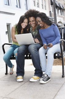 Friends sitting on bench using laptop