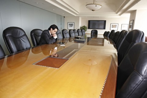 Hispanic businessman sitting in empty conference room
