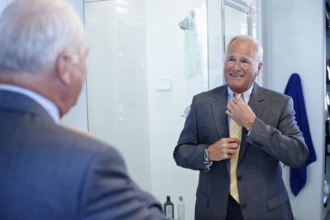 Caucasian man dressing in bathroom