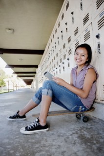 Chinese teenager on skateboard using digital tablet