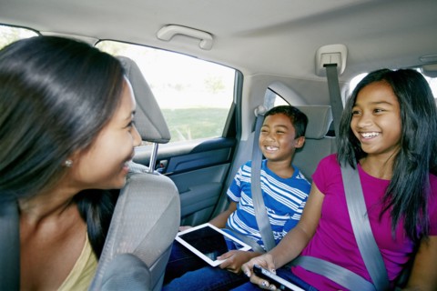 Mother watching children use technology in car