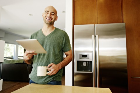 Hispanic man using tablet computer in kitchen