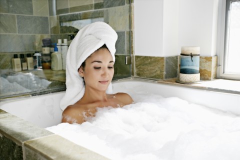 Mixed race woman having bubble bath