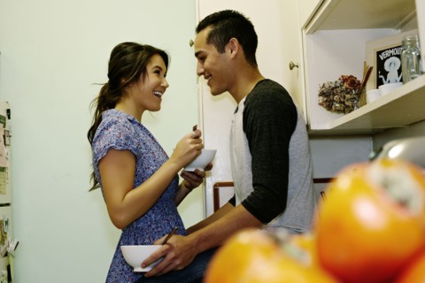 Smiling couple eating cereal in kitchen
