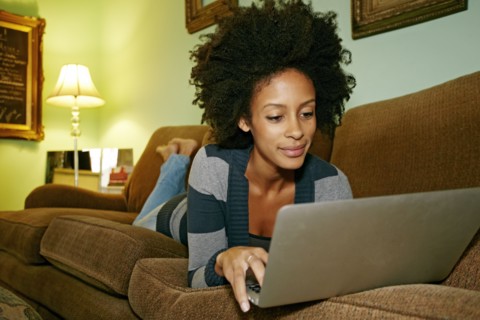 Mixed race woman using laptop on sofa